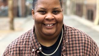a headshot of shea, wearing a checkered shirt over a black shirt